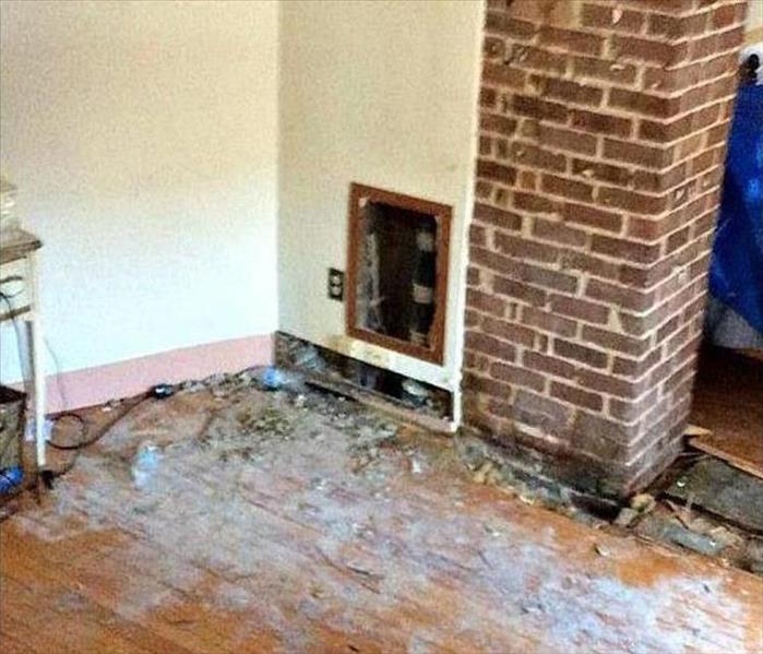 opened water access in wall by brick column with damaged wood floor